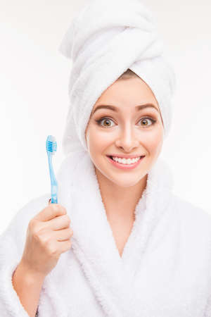 Smiling cute girl with towel on her head holding toothbrushの写真素材