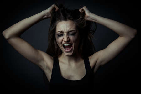 Portrait of a scared screaming girl, hands on the foreheadの写真素材