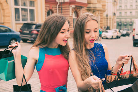 Beautiful stylish girl surprised  looking into shopping bagsの写真素材