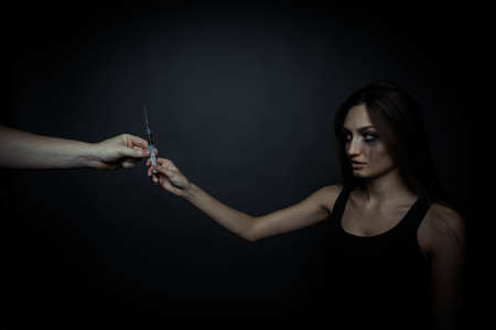 Young sad woman taking a syringe to drug useの写真素材