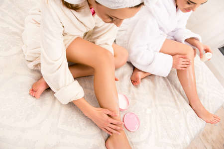 Nice young women smearing their legs with creamの写真素材