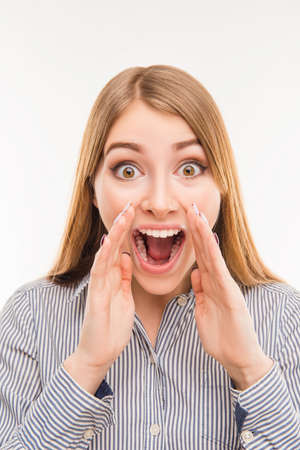 Great news! Cheerful young woman holding hand near mouth, close-up photo