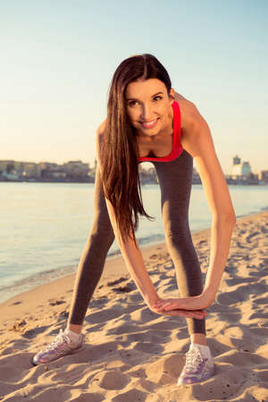 Happy young woman tiping on the beach to be flexible