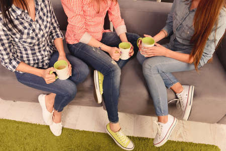Close up, top view photo of three women sitting on couch with cupsの写真素材