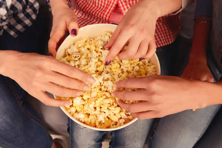 Close up, top view photo of women's hands taking popcornの写真素材