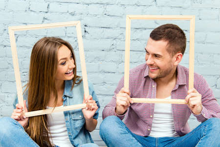 Close up portrait of man and woman looking on each other and holding frames