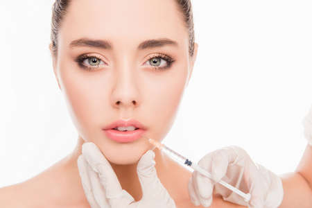 Beautiful girl doing an injection to increase  lips on  white background