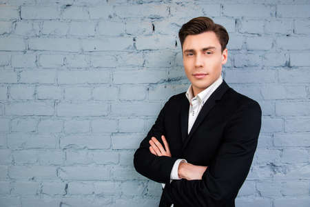 Portrait of serious man  with crossed hands on the background of wallの写真素材