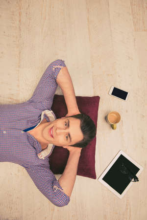 Top view photo of man lying on the floor with cup, phone, glasses and tabletの写真素材