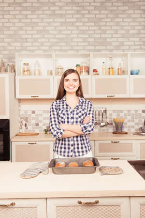 Young girl standing with crossed hands and baked cakesの写真素材