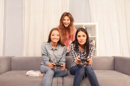 Three happy attractive girls playing video games at homeの写真素材