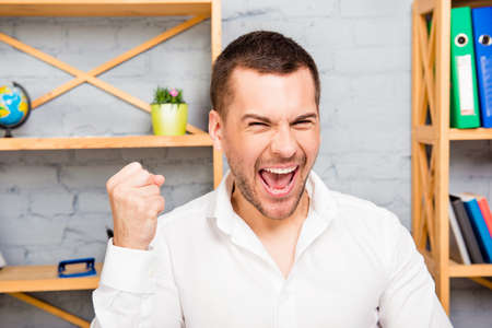 Close up portrait of happy worker screaming with raised fistの写真素材