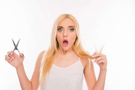 Shocked woman cutting her split ends on white backgroundの写真素材