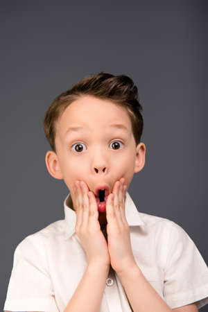 Close up portrait of little shocked boy touching his faceの写真素材