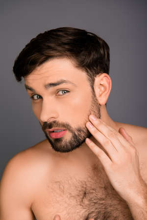 Handsome young man touching his face before shaving