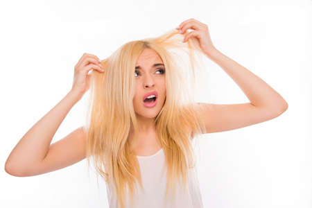 Surprised unhappy young woman looking at her damaged hairの写真素材