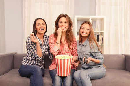 Happy smiling girls having gatherings with comedy and popcornの写真素材