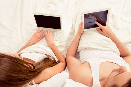 Top view of man and woman  working with laptop and tablet in bedの写真素材
