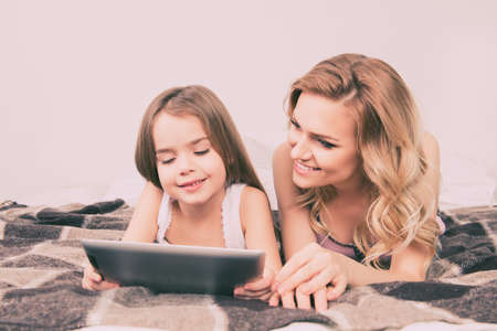 Close up portrait of small daughter and mother using tabletの写真素材