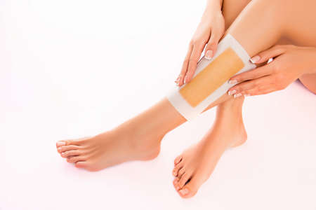 Woman using beeswax stripe to shave her leg, close up photoの写真素材