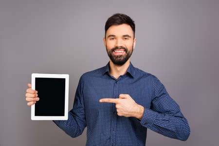 Handsome happy young businessman pointing on screen of tabletの写真素材