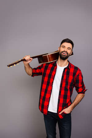Portrait of happy smiling man holding guitar on shoulderの写真素材