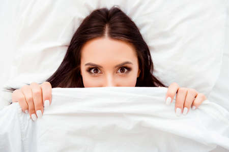Funny flirting girl hiding her face white coverletの写真素材