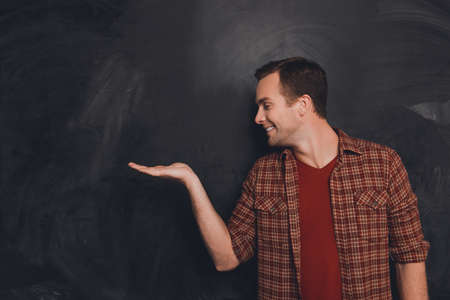 Smiling young man offering a product on  background of chalkboardの写真素材