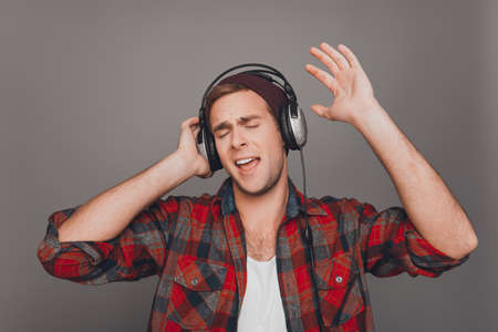 Portrait of man in cap and headphones listening music and singingの写真素材