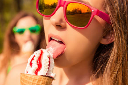 Close up portrait of beautiful girl in glasses eating ice creamの写真素材