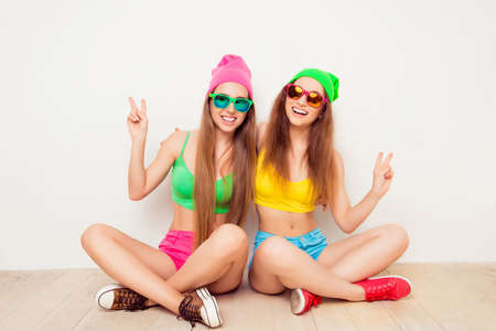 Portrait of two smiling women gesturing with two fingersの写真素材