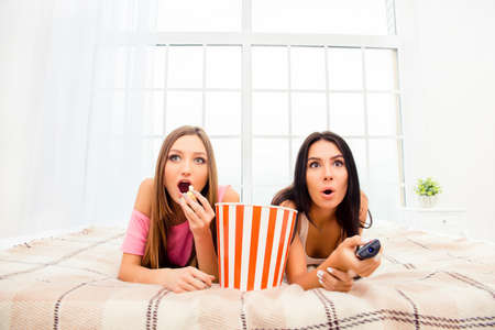 Wow! Two excited girls watching film and eating popcornの写真素材