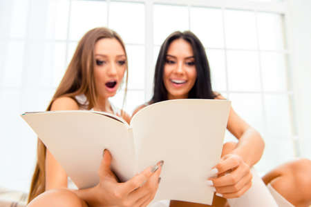 Wow! Two pretty girlfriends reading smth interesting in journalの写真素材