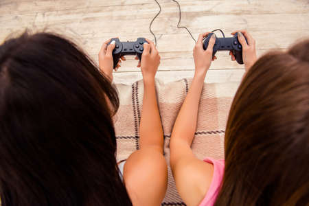 Close up portrait of two young woman lying with joysticksの写真素材