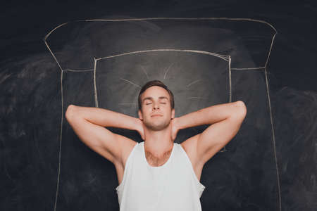 Young  man sleeping  on the background of chalkboardの写真素材