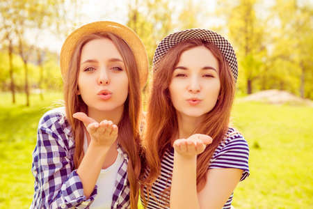 Portrait of beautiful girls in hats sending airy kissの写真素材