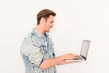 Side view portrait of cheerful guy typing on laptop