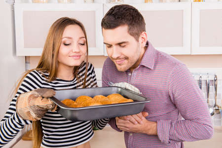 Young couple in love smelling baked cakes in the kitchenの写真素材