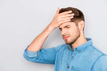 Handsome young tired man with migraine touching head