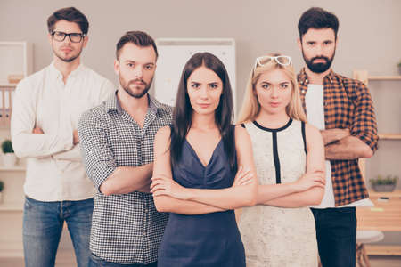 successful team of businesspeople   crossing hands  and looking at camera
