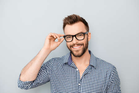 Cheerful smiling young businessman touching his glassesの写真素材