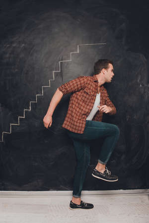 Portrait of young man going up on drawn stairs