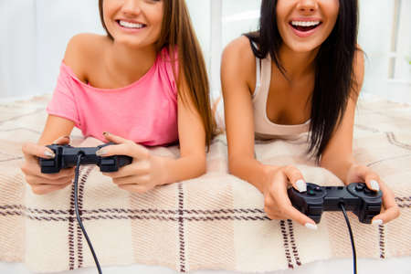 Close up photo of cheerful smiling women playing on joysticksの写真素材