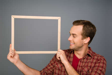 Smiling man in red  shirt  holding wooden frameの写真素材