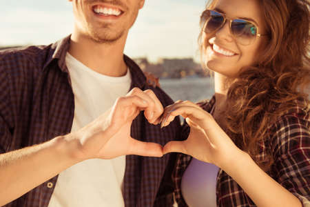 Close up portrait of man and woman making heart with fingersの写真素材