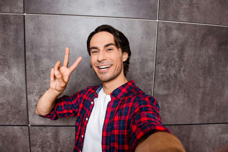 attractive young man makes selfie photo and showing two fingers