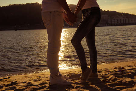 Close up photo of legs of man and woman watching sundown at the seasideの写真素材