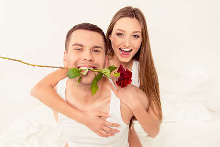 Close up portrait of happy couple in love. Man holding rose in mouthの写真素材