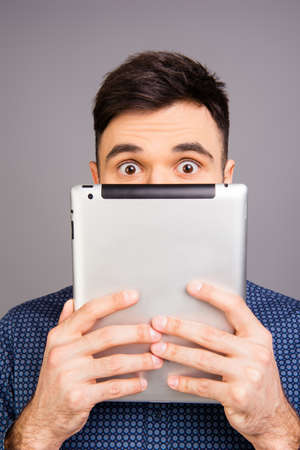 Close up portrait of young businessman hiding his face behind tabletの写真素材