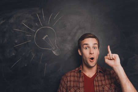 Smart man with raised finger on the background of blackboard with drawn lampbulbの写真素材